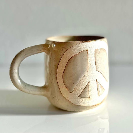off white stoneware mug with wax resist peace symbol by hey moon ceramics