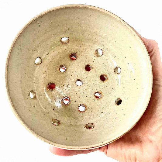 wheel-thrown ceramic bowl in off-white shiny glaze made by Hey Moon Ceramics. with holes for drainage