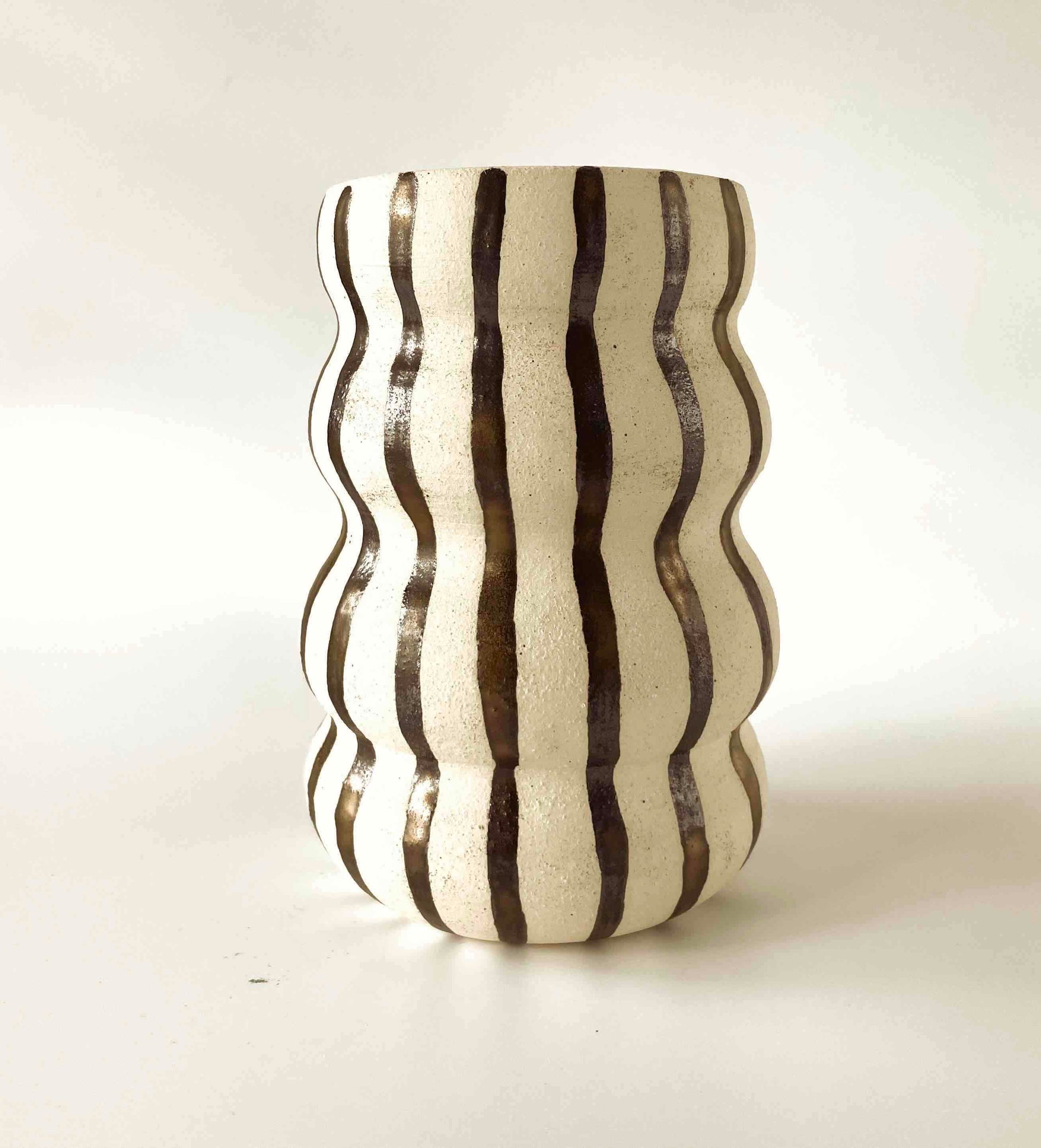 Medium sized white stonesare vase wheel-thrown by hey moon ceramics. With ribbed pattern and painted with bronze stripes on the exterior. interior is glazed on the inside with a clear glaze.
