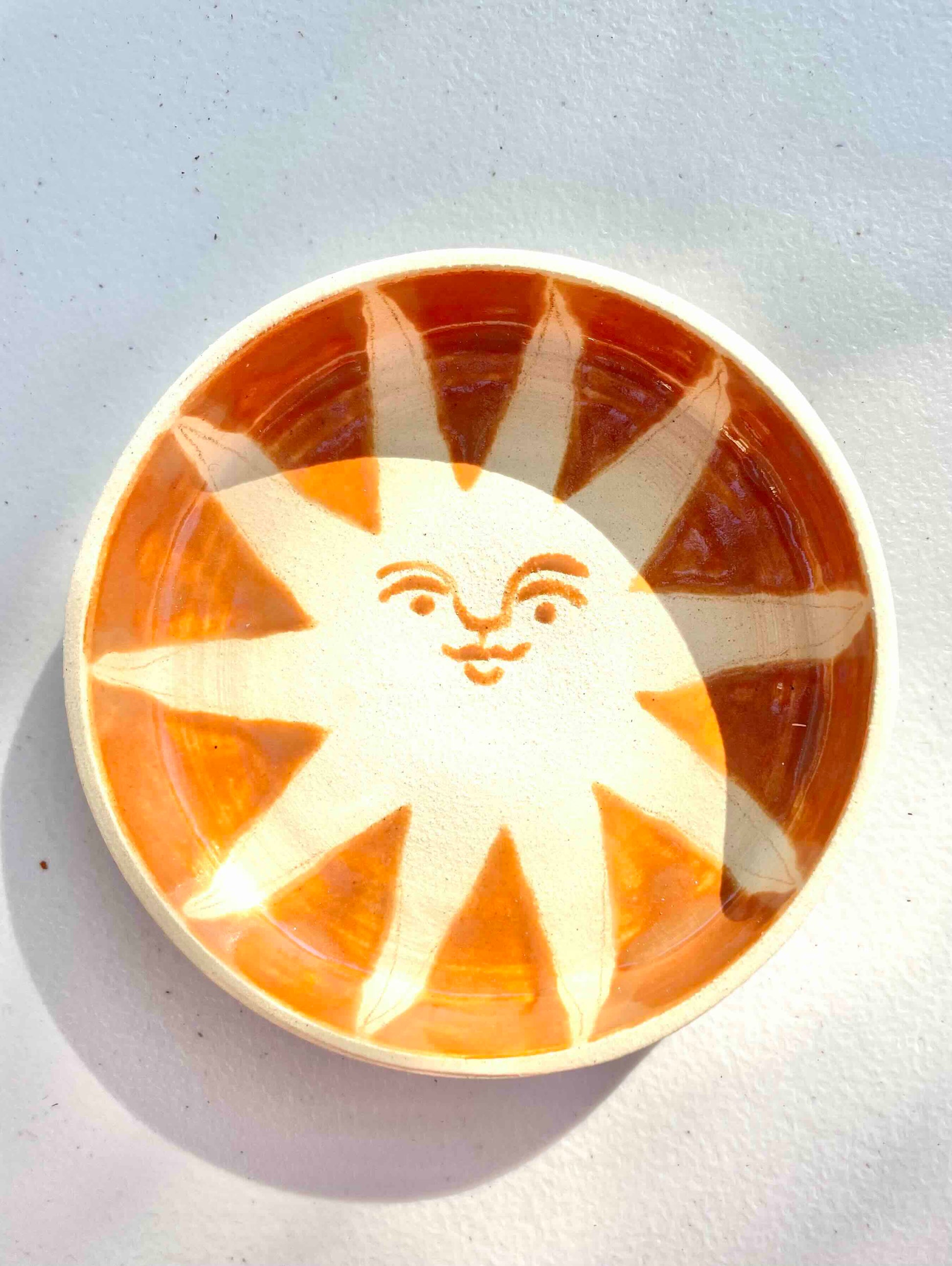 white stoneware catch all with handpainted orange sun with face by hey moon ceramics