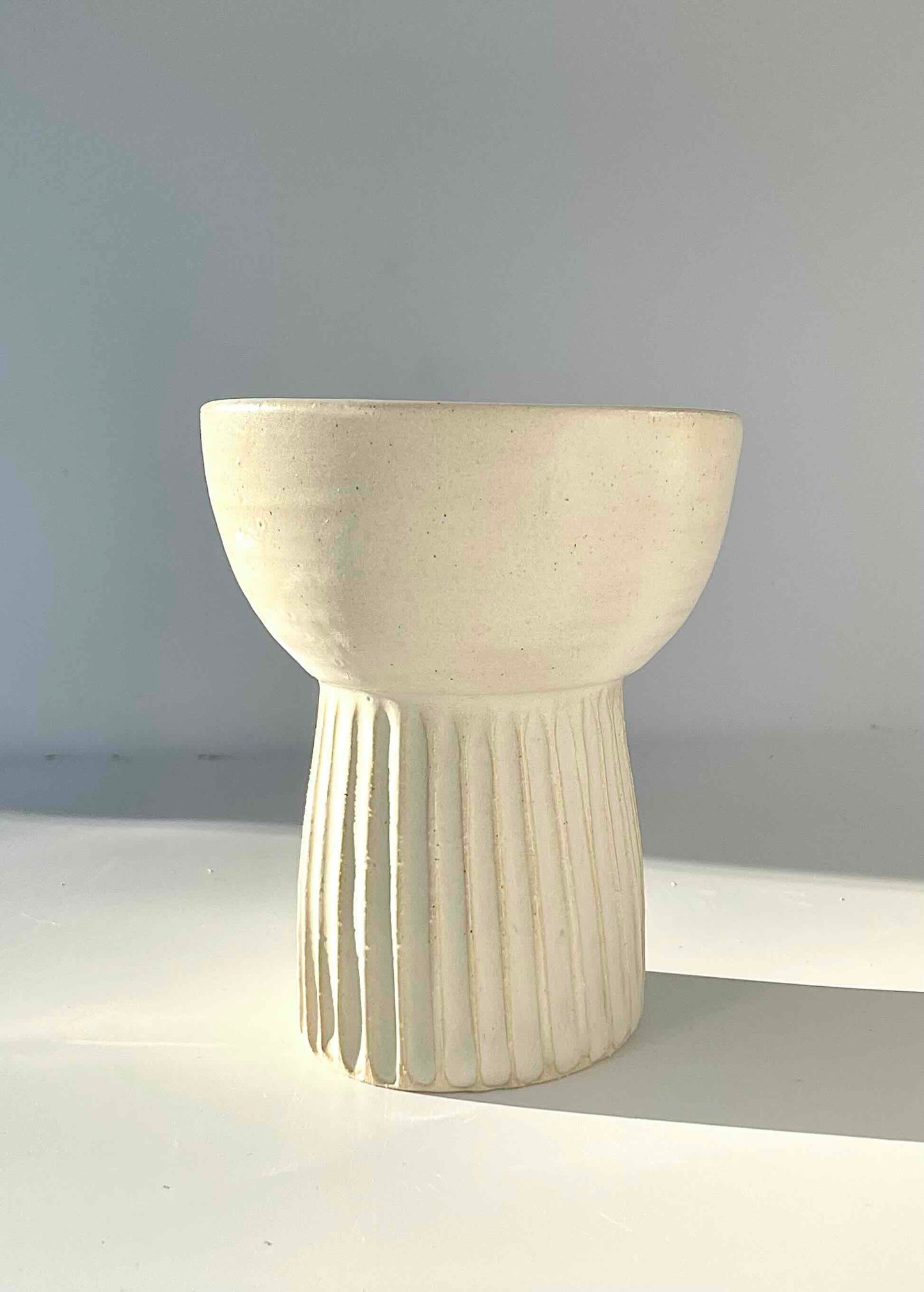 Matte white vase with ribbed detail at bottom and bowl top. Wheen thrown by Hey Moon Ceramics.