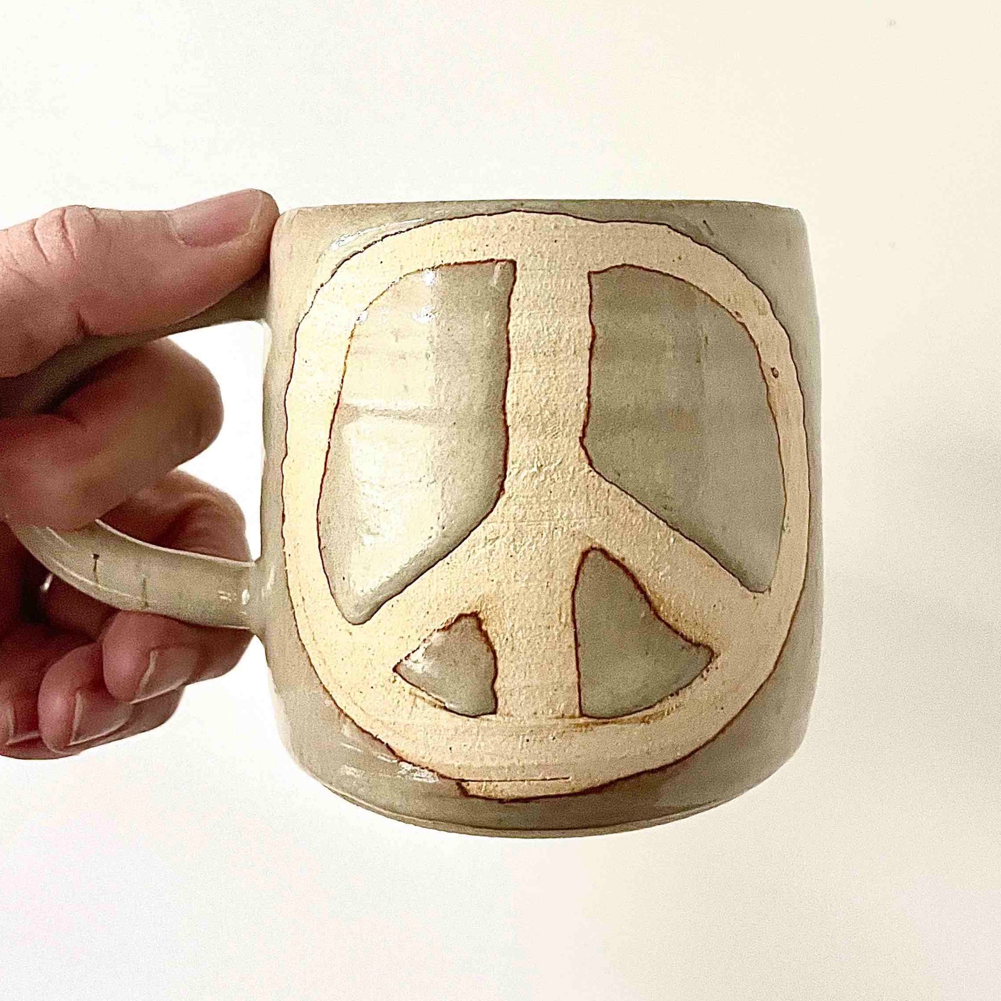 off-white glossy mug with peace symbol by hey moon ceramics