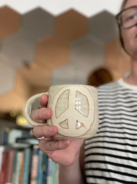 off white stoneware mug with wax resist peace symbol by hey moon ceramics
