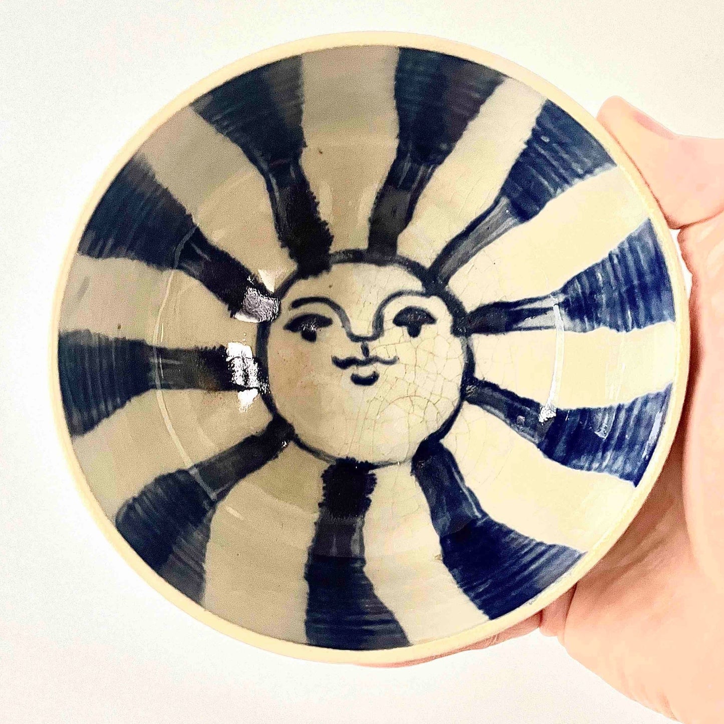 White stoneware bowl, wheel-thrown by Hey moon ceramics. Hand-painted on the interior with a blue sun which has a face. Clear glaze on inside only. Food safe